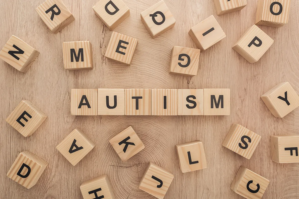 top view of autism lettering made of wooden cubes with different letters on wooden table